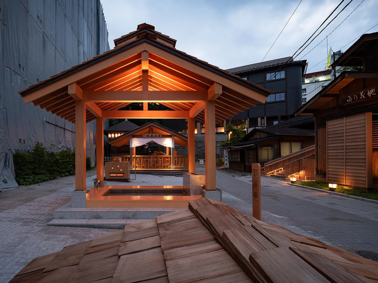 木造の屋根と照明が見える裏草津の広場の夕景